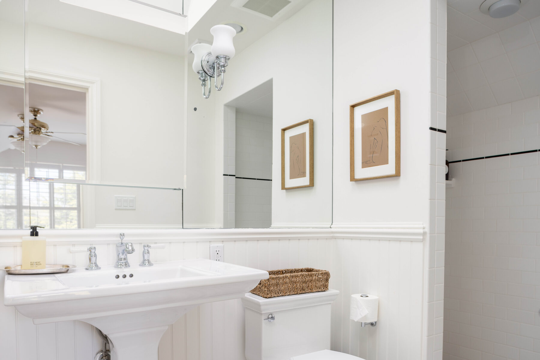 En-suite bath — pedestal sink against wainscoting and a wall of mirrors