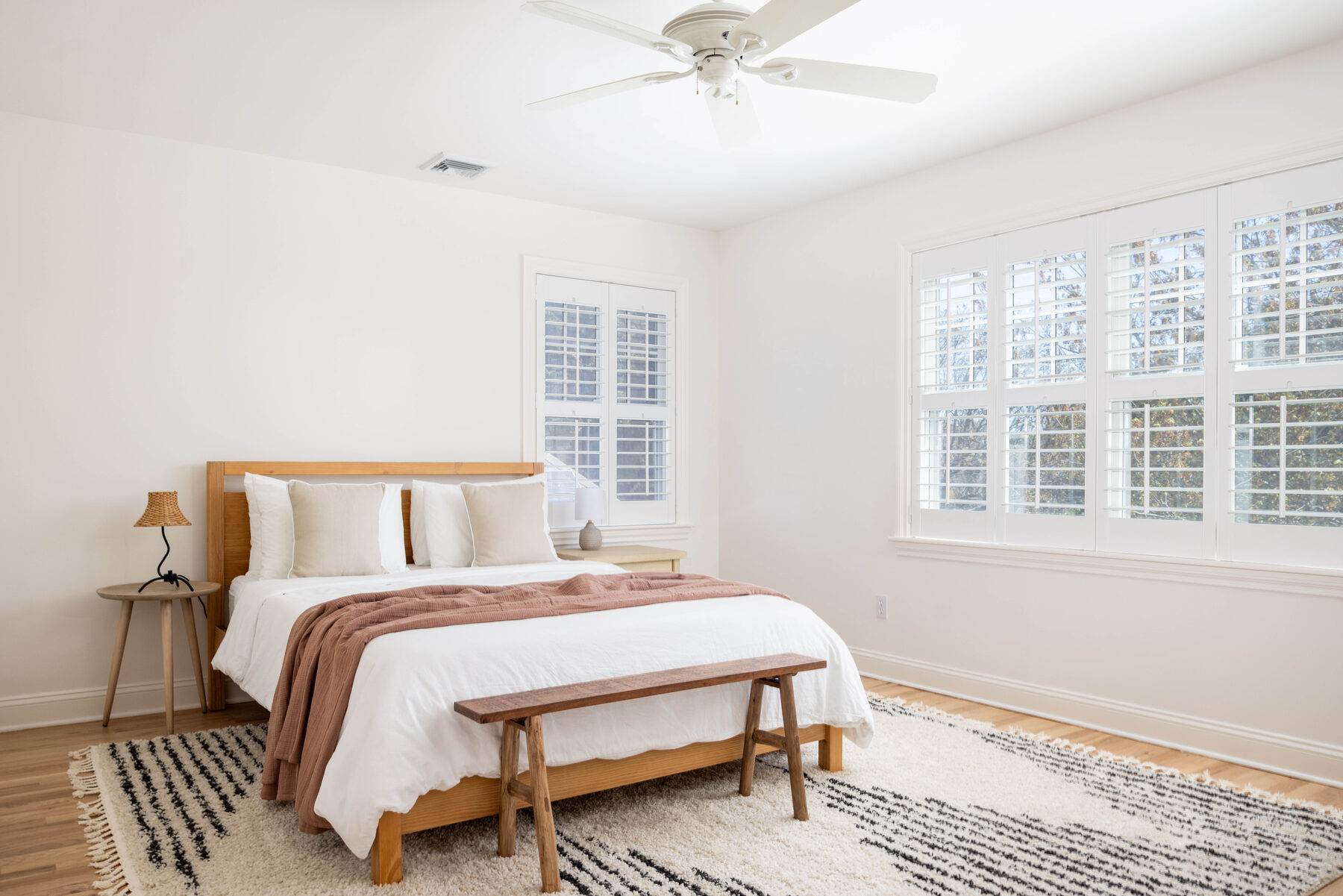 Guest room — linen-upholstered bed with a rust throw and layered rugs