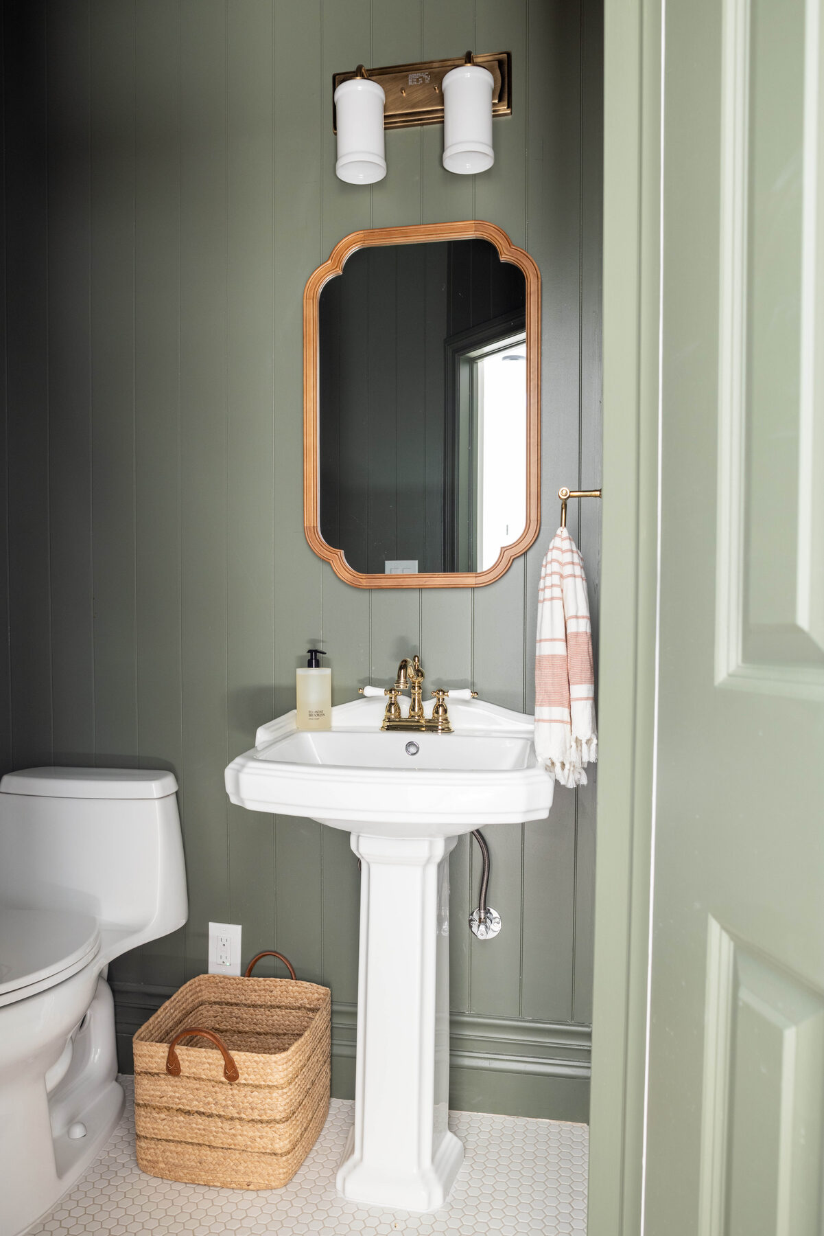 Powder room — sage-green door and warm brass hardware