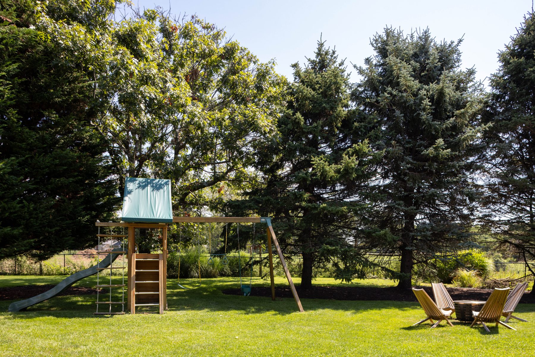 Play set — swings and slide under mature trees